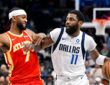 Dallas Mavericks guard Kyrie Irving dribbles past Atlanta Hawks guard Nickeil Alexander-Walker, who reaches across his arm.