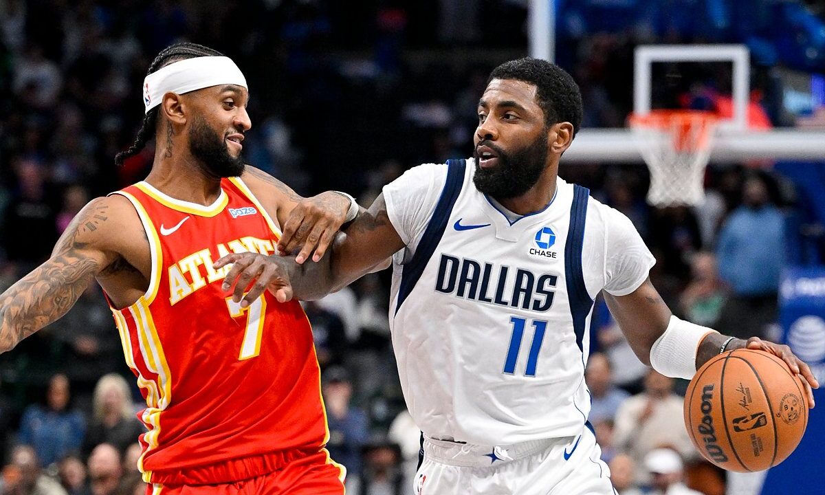 Dallas Mavericks guard Kyrie Irving dribbles past Atlanta Hawks guard Nickeil Alexander-Walker, who reaches across his arm.