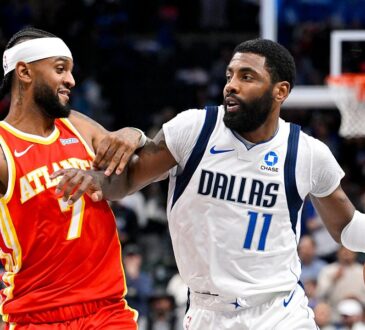 Dallas Mavericks guard Kyrie Irving dribbles past Atlanta Hawks guard Nickeil Alexander-Walker, who reaches across his arm.