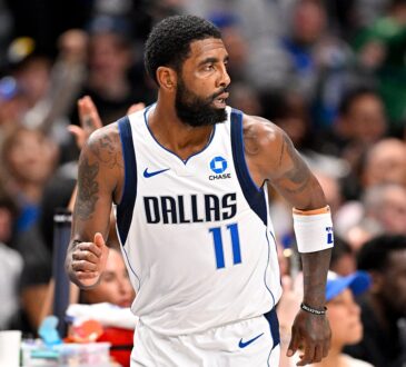 Dallas Mavericks guard Kyrie Irving glances over his shoulder while jogging down the court with his fist clenched.