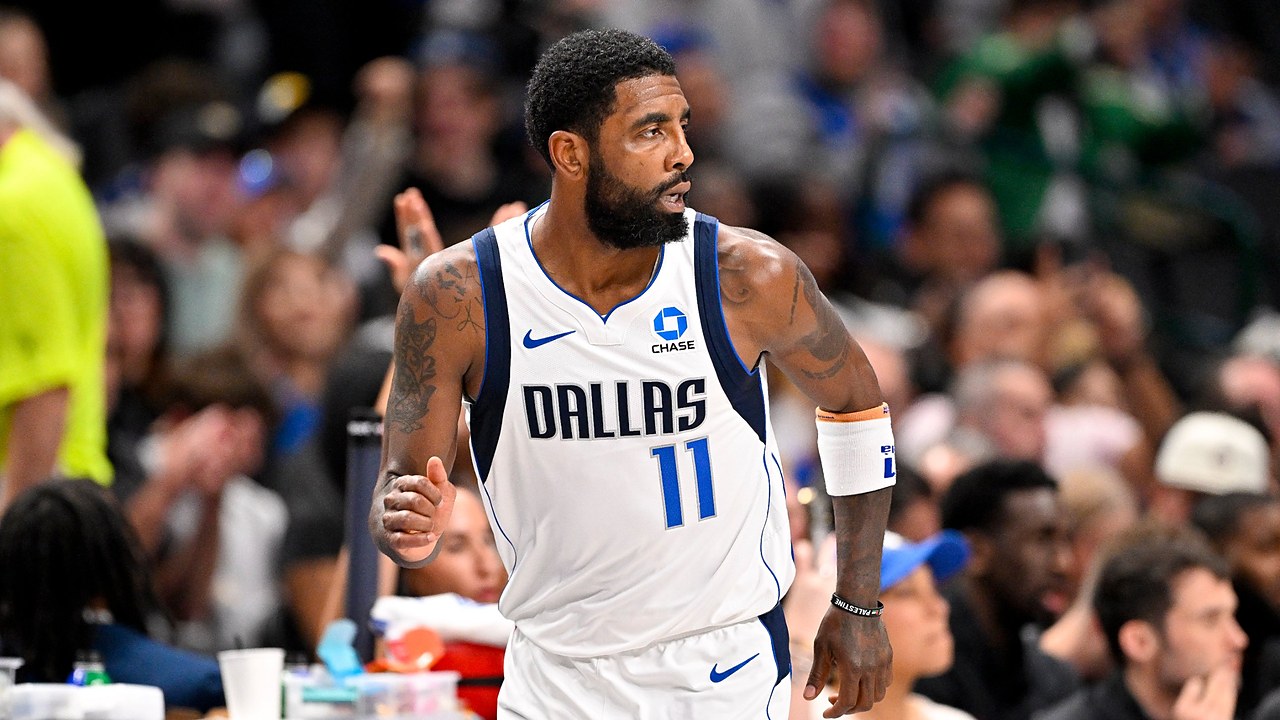 Dallas Mavericks guard Kyrie Irving glances over his shoulder while jogging down the court with his fist clenched.