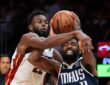 Dallas Mavericks guard Kyrie Irving grimaces as Miami Heat forward Andrew Wiggins reaches across him to grab the ball.