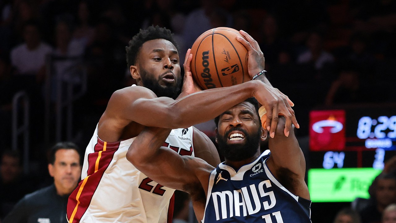 Dallas Mavericks guard Kyrie Irving grimaces as Miami Heat forward Andrew Wiggins reaches across him to grab the ball.