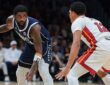 Dallas Mavericks guard Kyrie Irving dribbles with his right hand as Miami Heat guard Dru Smith crouches to defend.