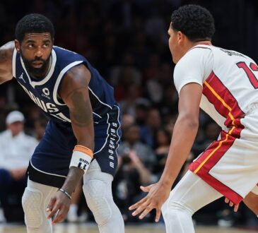 Dallas Mavericks guard Kyrie Irving dribbles with his right hand as Miami Heat guard Dru Smith crouches to defend.