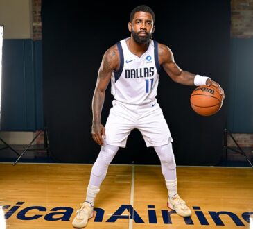 Mavericks guard Kyrie Irving poses in a low dribbling stance in his white home uniform on a studio court.