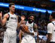 Dallas Mavericks guard Kyrie Irving clutches the ball as teammates Dwight Powell and P.J. Washington close in.