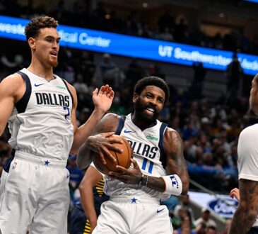 Dallas Mavericks guard Kyrie Irving clutches the ball as teammates Dwight Powell and P.J. Washington close in.