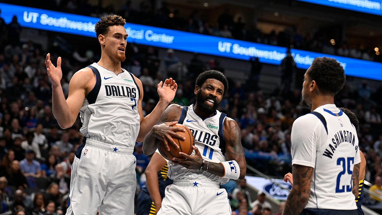 Dallas Mavericks guard Kyrie Irving clutches the ball as teammates Dwight Powell and P.J. Washington close in.