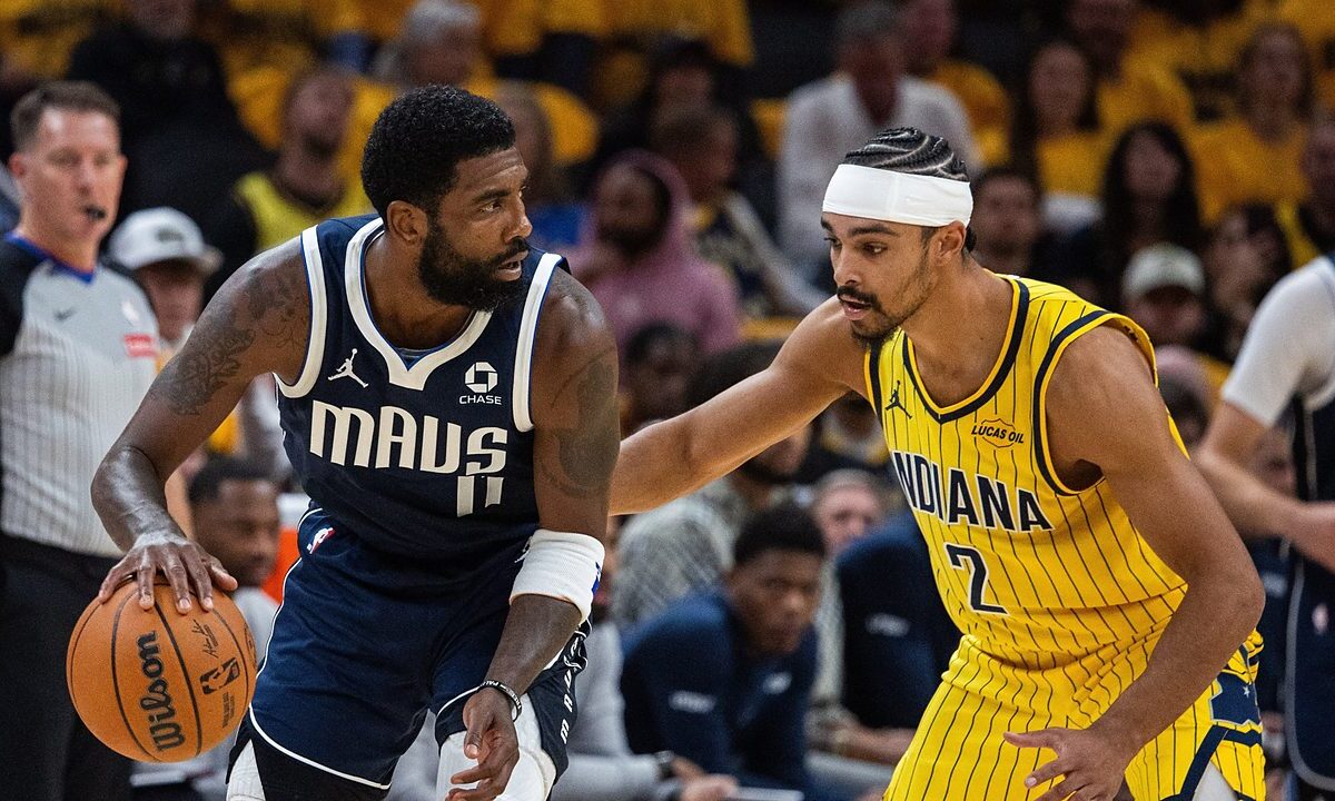 Dallas Mavericks guard Kyrie Irving dribbles low with his right hand as Indiana Pacers guard Andrew Nembhard reaches in to defend.