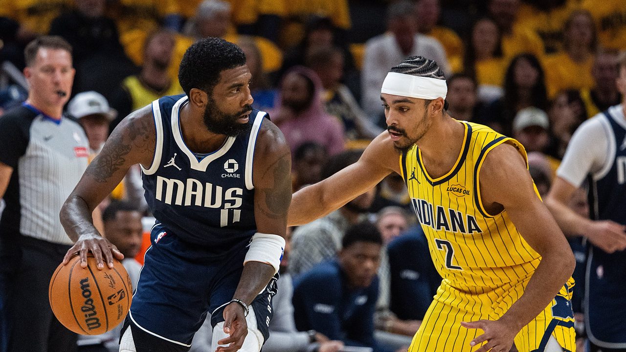 Dallas Mavericks guard Kyrie Irving dribbles low with his right hand as Indiana Pacers guard Andrew Nembhard reaches in to defend.