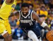 Dallas Mavericks guard Kyrie Irving drives low past Indiana Pacers guard Quenton Jackson, who reaches high with one arm.