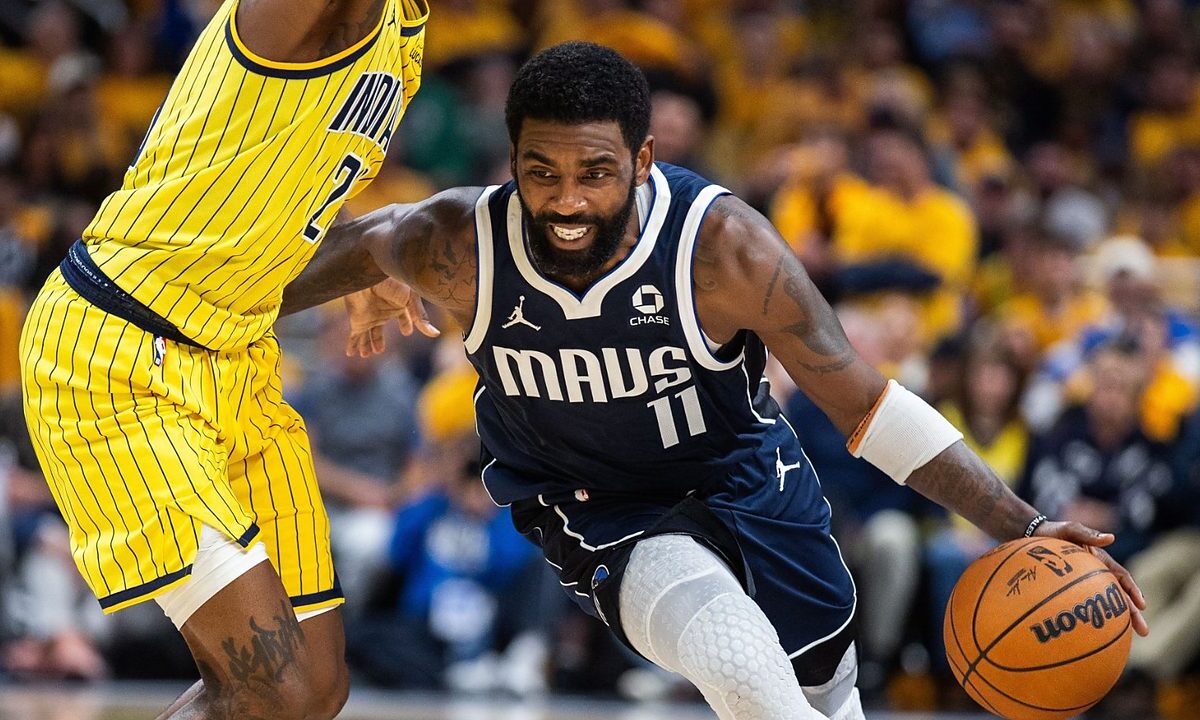 Dallas Mavericks guard Kyrie Irving drives low past Indiana Pacers guard Quenton Jackson, who reaches high with one arm.