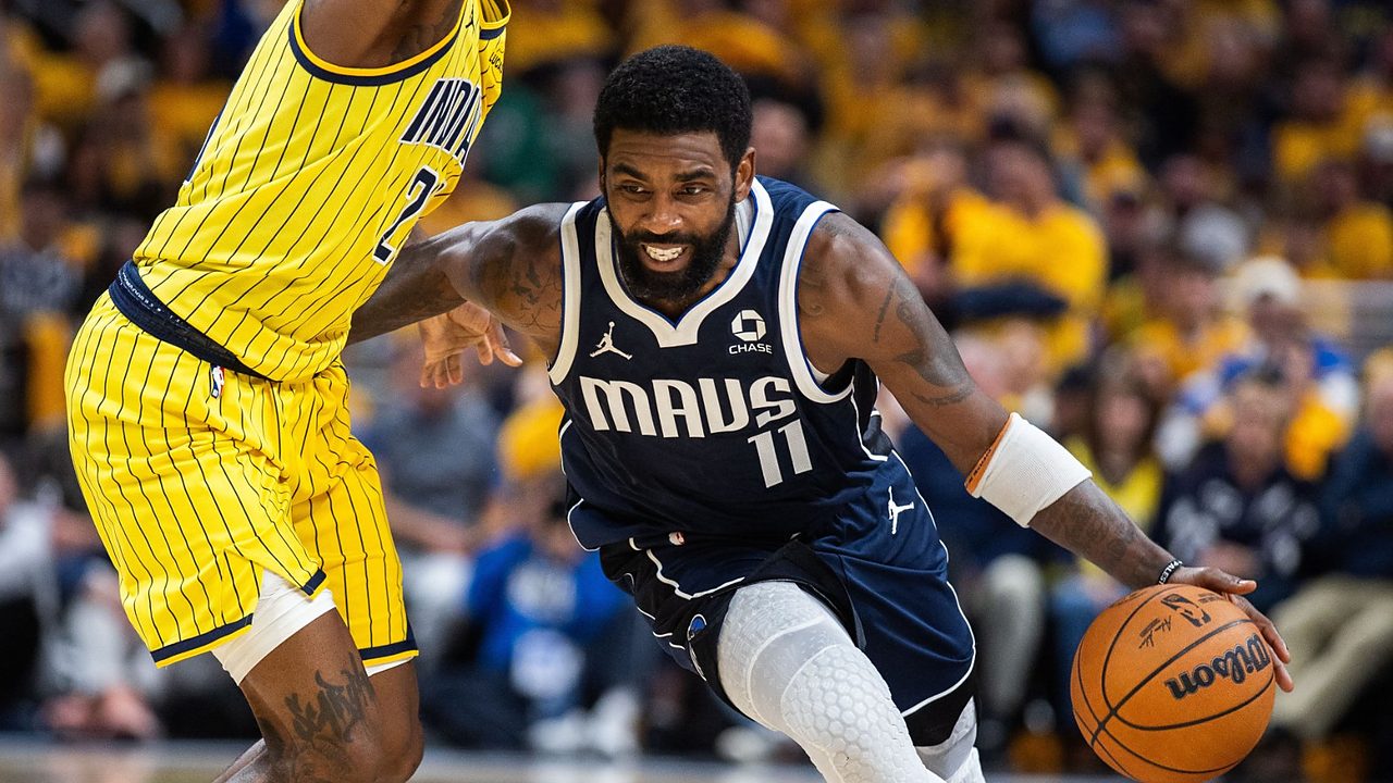 Dallas Mavericks guard Kyrie Irving drives low past Indiana Pacers guard Quenton Jackson, who reaches high with one arm.