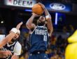 Dallas Mavericks guard Kyrie Irving rises for a jump shot as Indiana Pacers guard Andrew Nembhard reaches past a teammate.