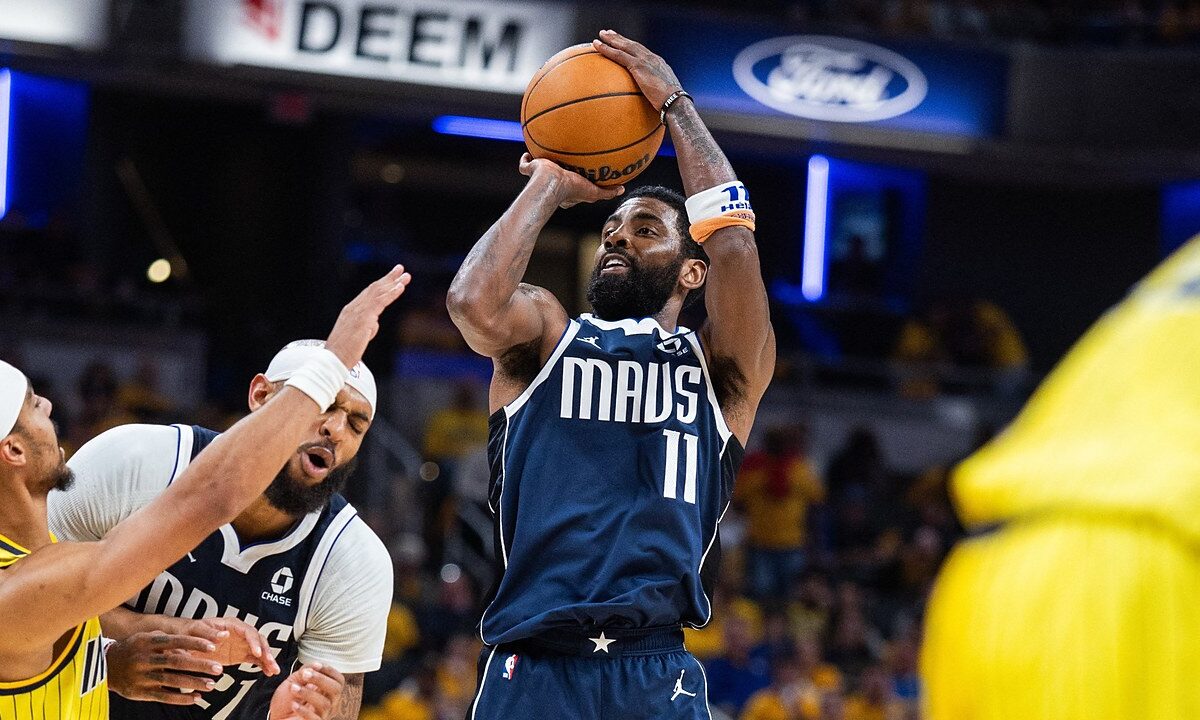 Dallas Mavericks guard Kyrie Irving rises for a jump shot as Indiana Pacers guard Andrew Nembhard reaches past a teammate.
