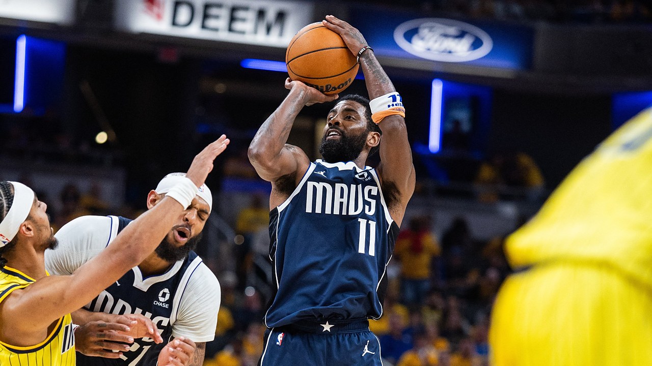 Dallas Mavericks guard Kyrie Irving rises for a jump shot as Indiana Pacers guard Andrew Nembhard reaches past a teammate.