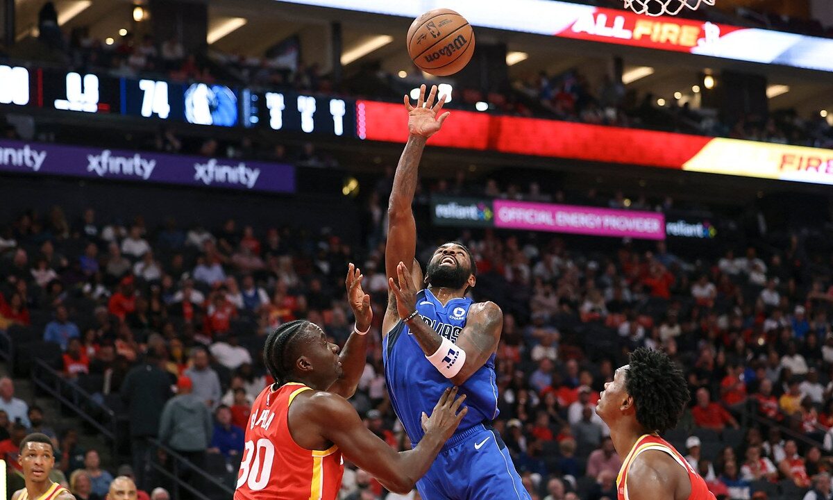 Dallas Mavericks guard Kyrie Irving releases a one-handed shot over Houston Rockets center Clint Capela near the basket.