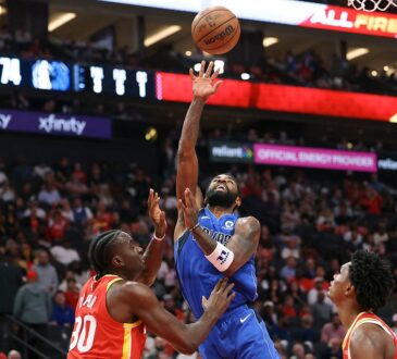 Dallas Mavericks guard Kyrie Irving releases a one-handed shot over Houston Rockets center Clint Capela near the basket.