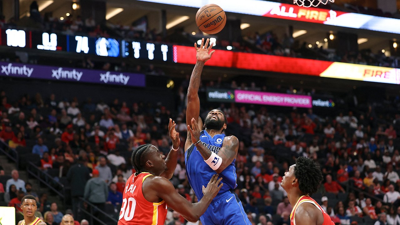 Dallas Mavericks guard Kyrie Irving releases a one-handed shot over Houston Rockets center Clint Capela near the basket.