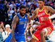 Mavericks guard Kyrie Irving dribbles low as Rockets forward Jabari Smith Jr. defends in front of a packed crowd.