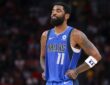 Dallas Mavericks guard Kyrie Irving closes his eyes and tugs at the bottom of his jersey during a pause in play.