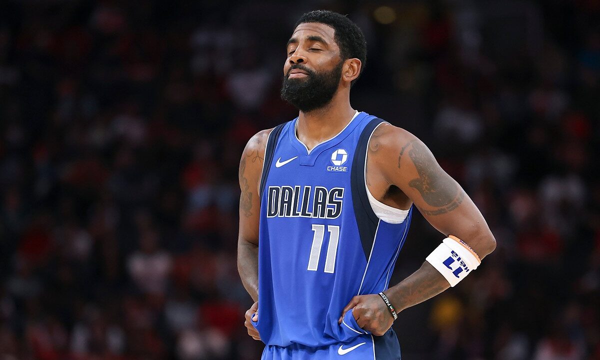 Dallas Mavericks guard Kyrie Irving closes his eyes and tugs at the bottom of his jersey during a pause in play.