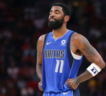 Dallas Mavericks guard Kyrie Irving closes his eyes and tugs at the bottom of his jersey during a pause in play.