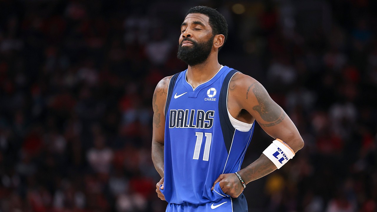Dallas Mavericks guard Kyrie Irving closes his eyes and tugs at the bottom of his jersey during a pause in play.