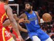 Dallas Mavericks guard Kyrie Irving dribbles past Houston Rockets defenders with the ball in his left hand.