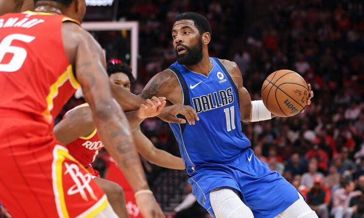 Dallas Mavericks guard Kyrie Irving dribbles past Houston Rockets defenders with the ball in his left hand.