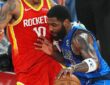 Mavericks guard Kyrie Irving lowers his shoulder and drives into Rockets forward Jabari Smith Jr. while dribbling.