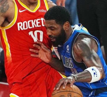 Mavericks guard Kyrie Irving lowers his shoulder and drives into Rockets forward Jabari Smith Jr. while dribbling.