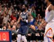 Mavericks guard Kyrie Irving gestures in celebration as fans cheer behind him.