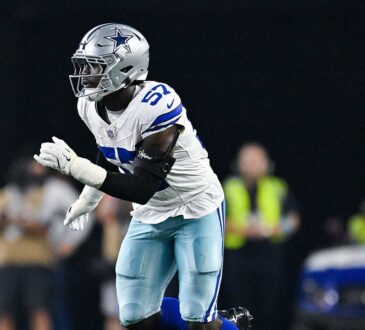 Dallas Cowboys linebacker Malachi Lawrence charges forward off the edge with his hands up during a play.