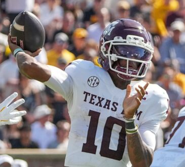 Texas A&M quarterback Marcel Reed cocks his arm back to throw as a defender's gloved hand reaches in from the left.