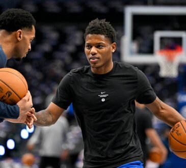Dallas Mavericks guard Marcus Sasser dribbles during warmups in a black Mavericks T-shirt as a staff member works with him.