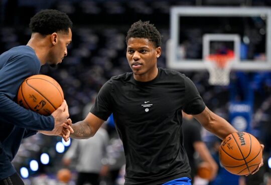 Dallas Mavericks guard Marcus Sasser dribbles during warmups in a black Mavericks T-shirt as a staff member works with him.
