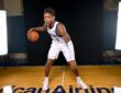 Dallas Mavericks guard Marcus Sasser crouches in a dribbling stance with the ball on a hardwood court between studio lights.