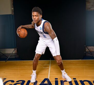Dallas Mavericks guard Marcus Sasser crouches in a dribbling stance with the ball on a hardwood court between studio lights.