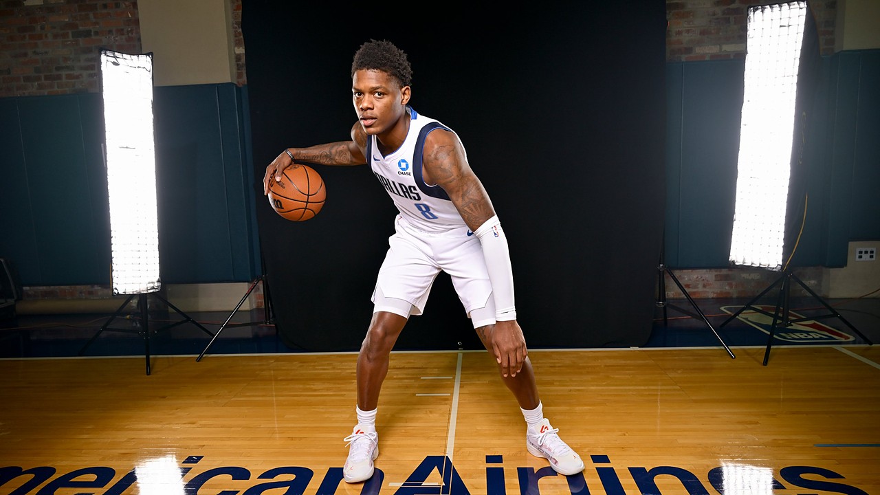 Dallas Mavericks guard Marcus Sasser crouches in a dribbling stance with the ball on a hardwood court between studio lights.
