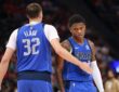 Dallas Mavericks forward Cooper Flagg reaches out to slap hands with guard Marcus Sasser during a stop in play.