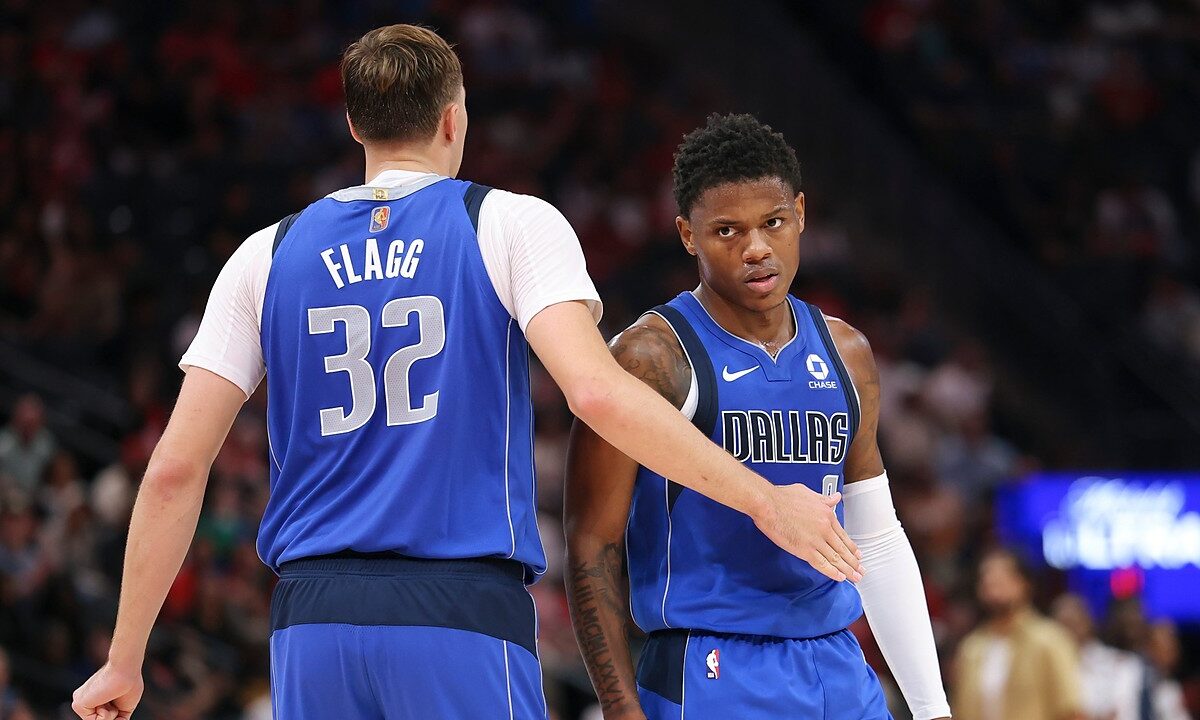 Dallas Mavericks forward Cooper Flagg reaches out to slap hands with guard Marcus Sasser during a stop in play.
