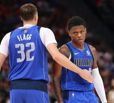 Dallas Mavericks forward Cooper Flagg reaches out to slap hands with guard Marcus Sasser during a stop in play.