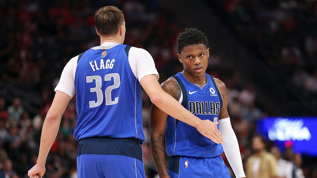 Dallas Mavericks forward Cooper Flagg reaches out to slap hands with guard Marcus Sasser during a stop in play.