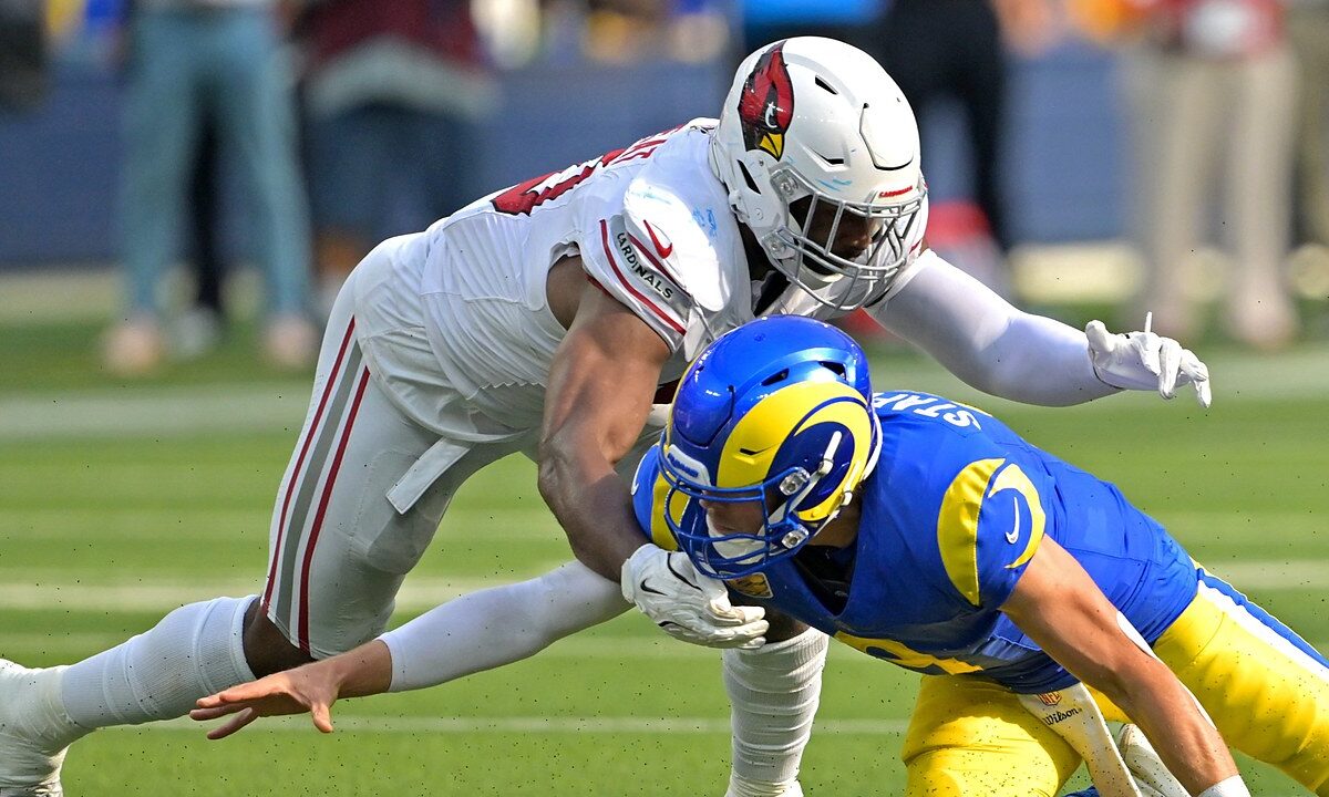 Los Angeles Rams quarterback Matthew Stafford falls forward as Arizona Cardinals linebacker Josh Sweat reaches over him.