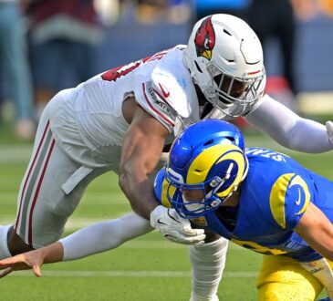 Los Angeles Rams quarterback Matthew Stafford falls forward as Arizona Cardinals linebacker Josh Sweat reaches over him.