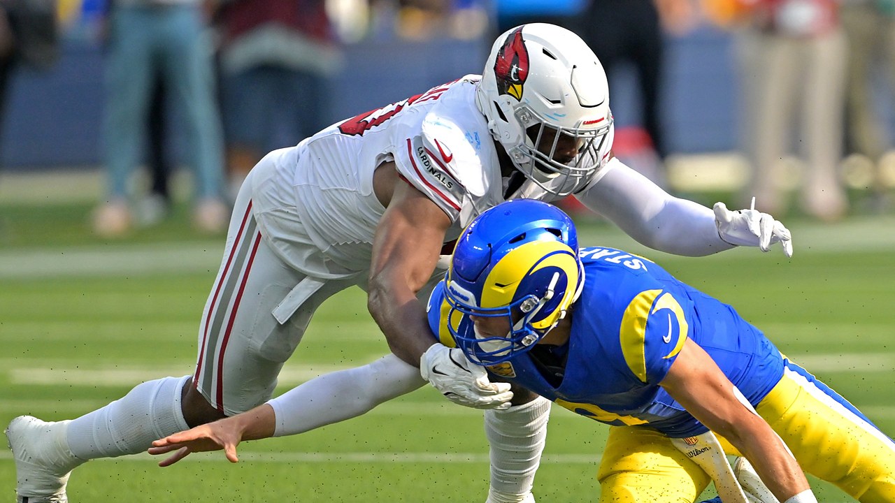 Los Angeles Rams quarterback Matthew Stafford falls forward as Arizona Cardinals linebacker Josh Sweat reaches over him.