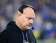 Vikings assistant coach Mike Pettine, wearing a headset and team hoodie, looks on from the sideline.
