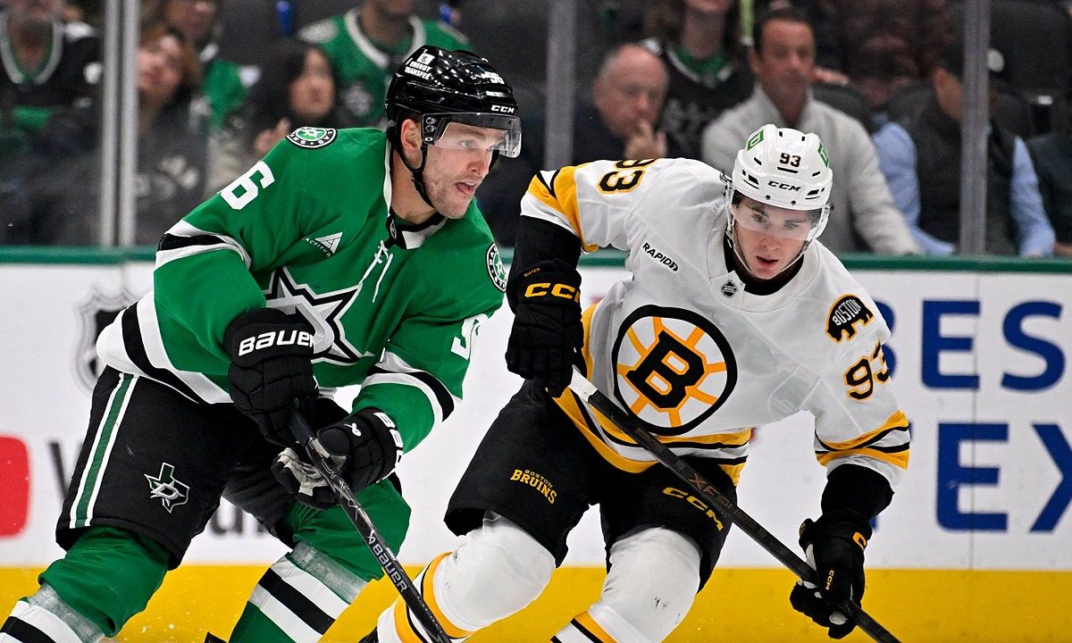 Dallas Stars right wing Mikko Rantanen carries the puck up ice as Boston Bruins center Fraser Minten skates alongside.